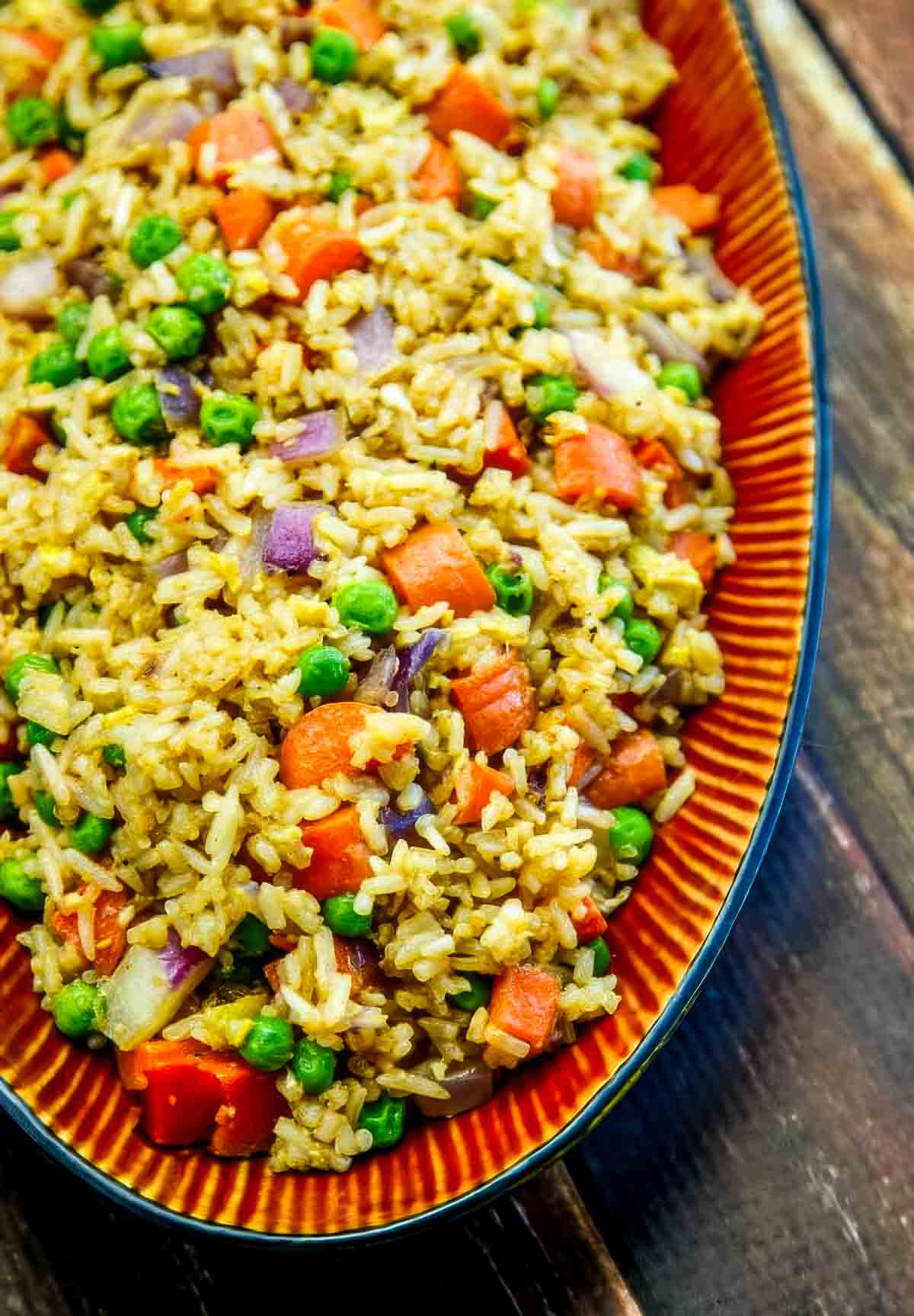 an overhead shot of an asian-style platter filled with fried rice on a wooden table