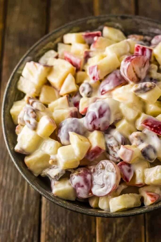 a closeup of a metal bowl filled with fall fruit salad on a wooden table