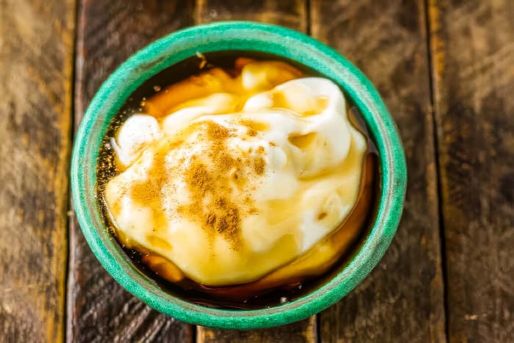 a small dish with yogurt, maple syrup, and cinnamon ready to be mixed together to form a creamy dressing for a fall fruit salad