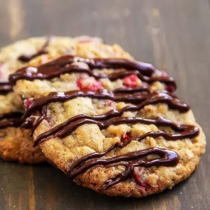 cranberry oatmeal chocolate chip cookies that have just been drizzled with melted chocolate