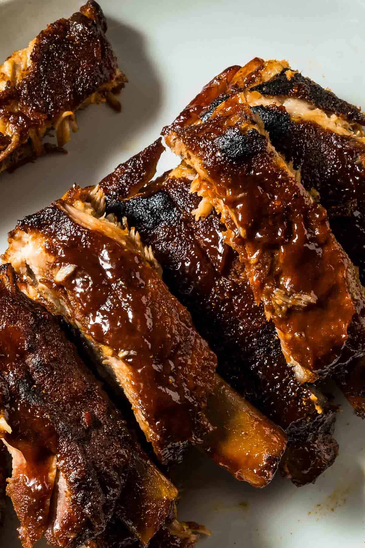 How to Cook Ribs in the Oven – Tender, Juicy & Easy oven baked BBQ ribs with a rich, sticky glaze on a white plate, showcasing tender, flavorful meat perfect for barbecue lovers.