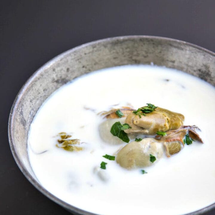 oyster stew with canned oysters in a vintage silver bowl on a black background