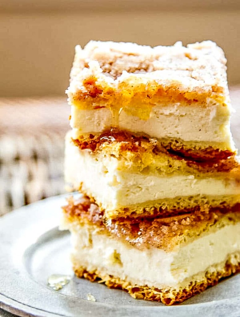 Sopapilla Cheesecake with Crescent Rolls (Quick & Delicious) Overhead shot of sopapilla cheesecake squares stacked with layers of flaky crust and cream cheese filling