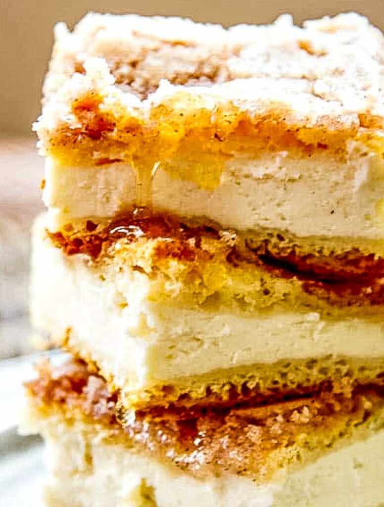 Close-up of stacked sopapilla cheesecake bars with a golden cinnamon-sugar crust and creamy filling