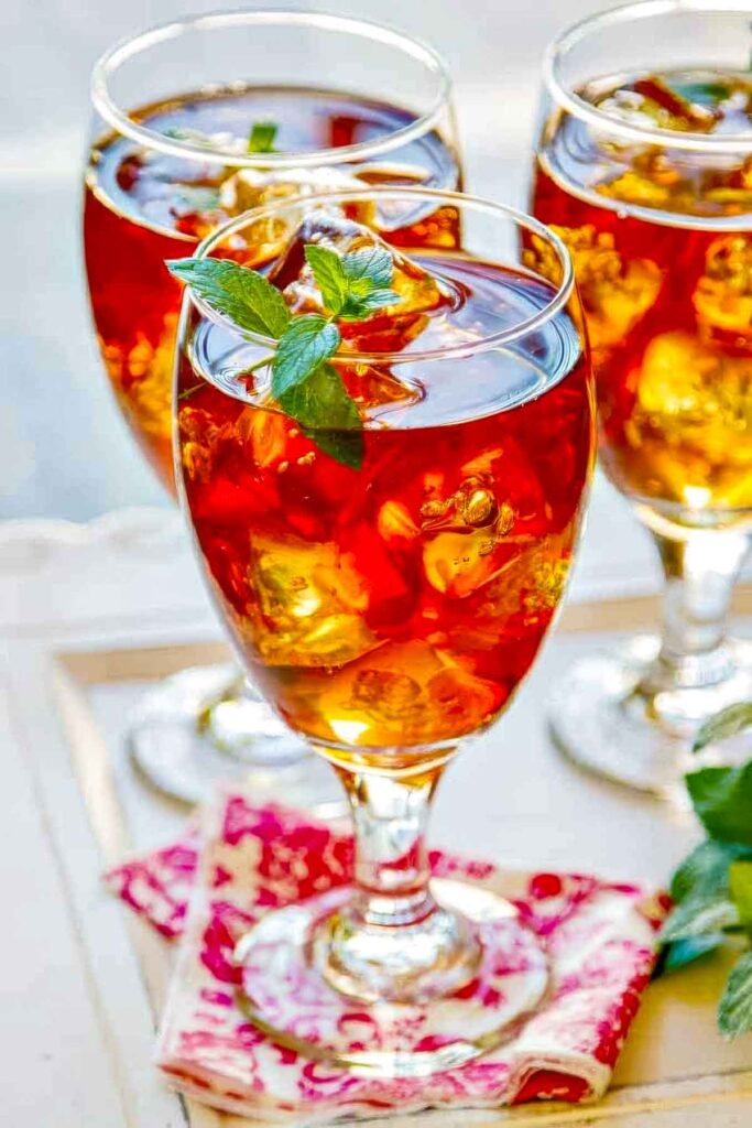 three glasses of sweet tea vodka with a sprig of fresh mint on a pretty pink and white napkin