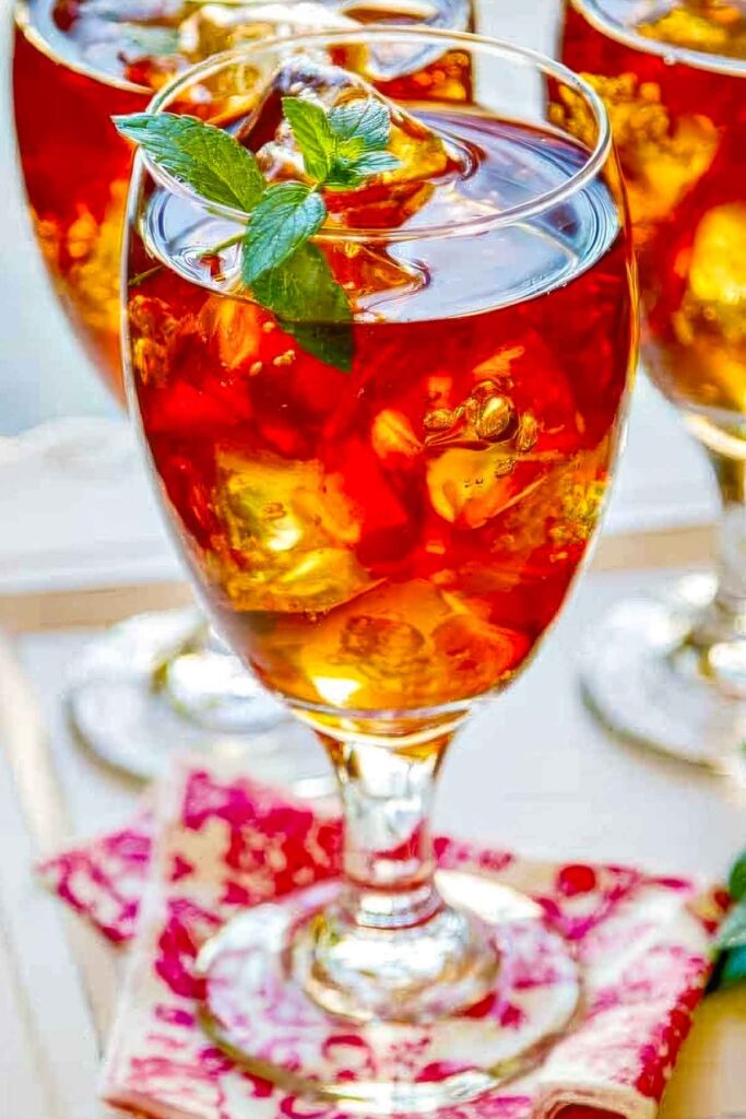 three glasses of homemade sweet tea vodka with a sprig of fresh mint on a pretty pink and white napkin