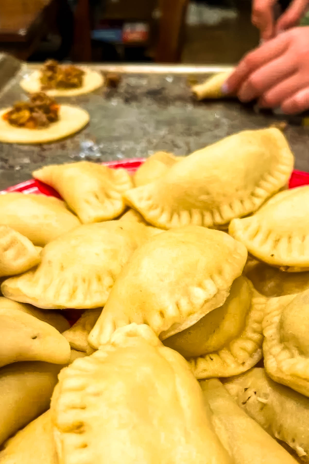 step 12 of a pastechi recipe: a round of dough being stuffed with the filling before baking