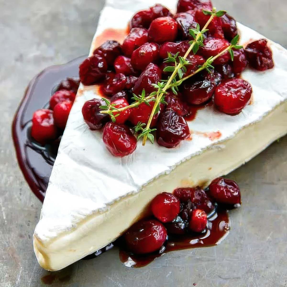 Cranberry Baked Brie (15-minute recipe) a wedge of cranberry baked brie garnished with fresh sprigs of thyme