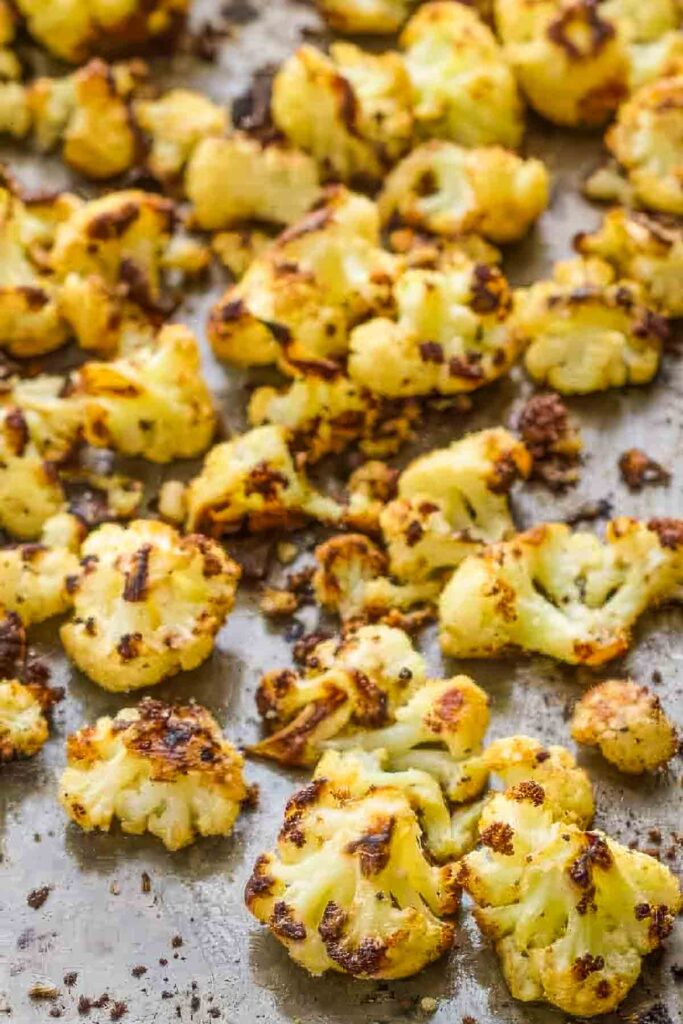 Golden brown parmesan roasted cauliflower on a baking sheet, showing crispy, caramelized edges.