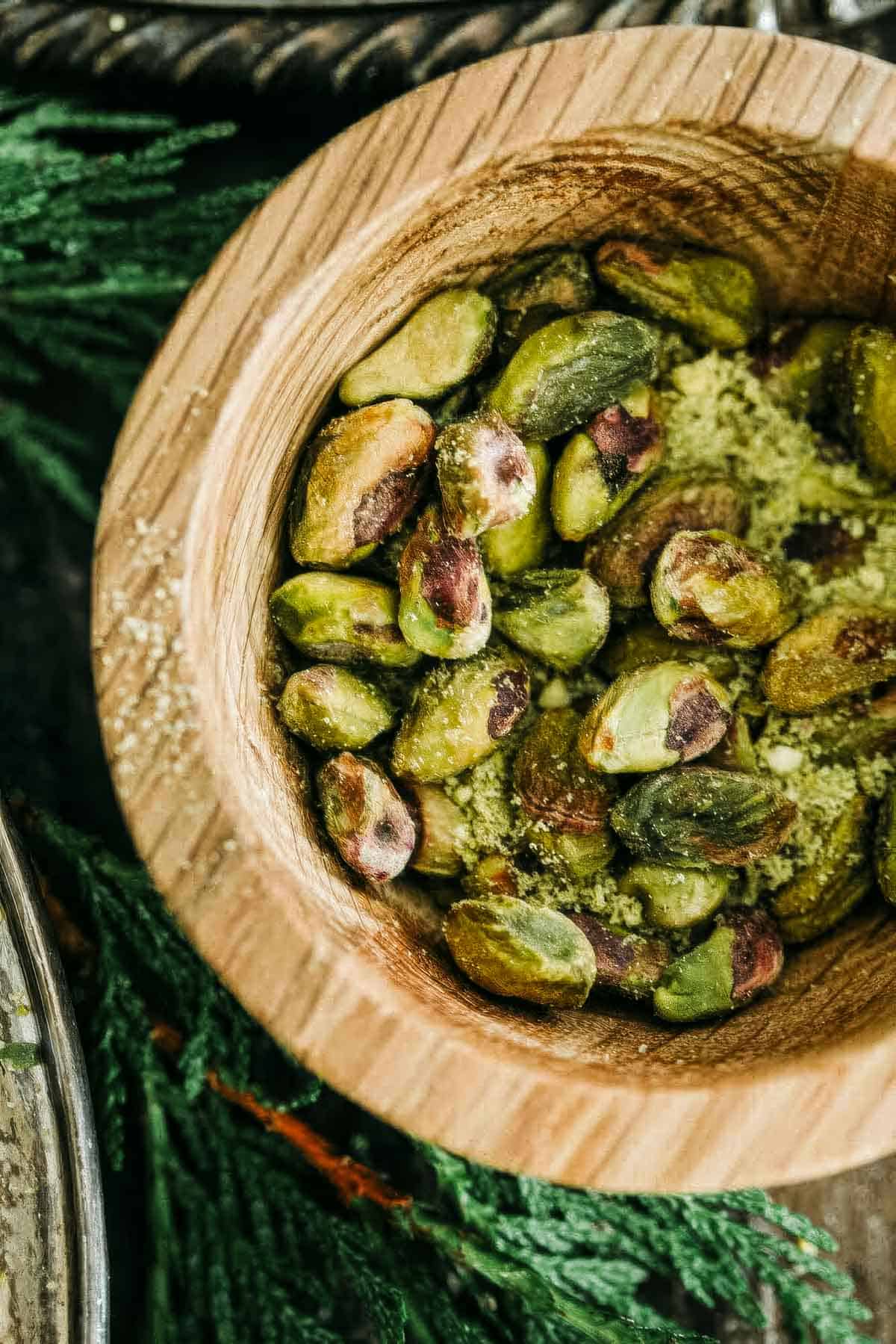 a wooden bowl filled with salty shelled pistachios
