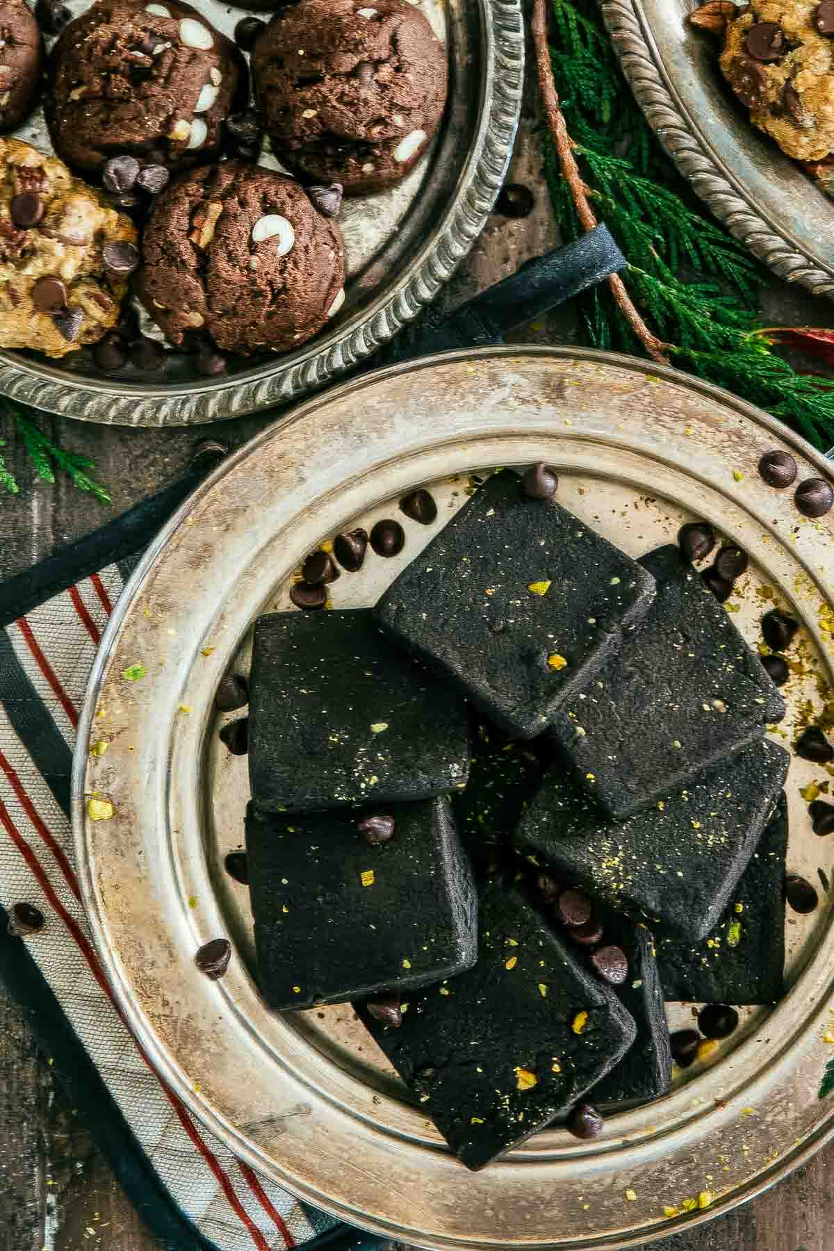 a round, vintage silver plate filled with chocolate shortbread cookies with another plate of cookies in the background