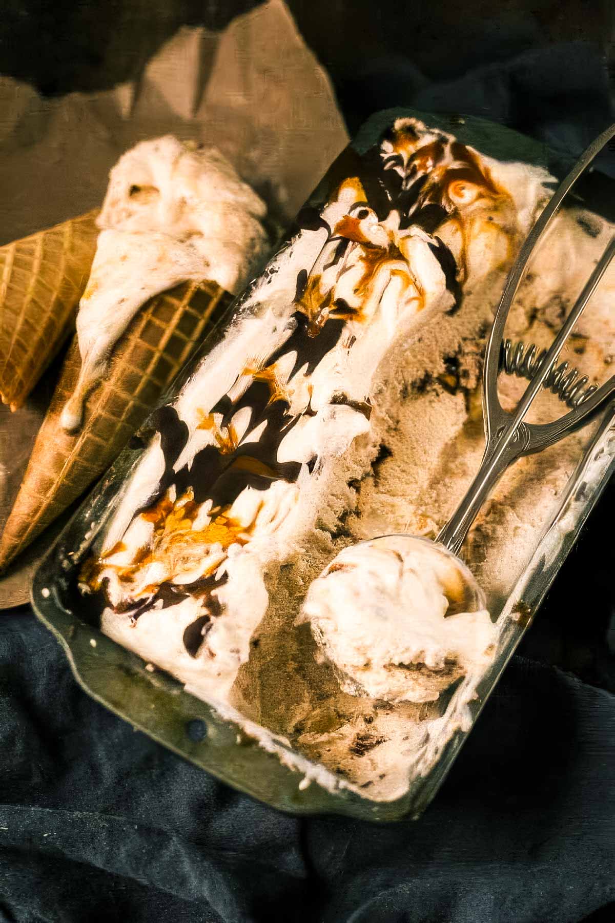 Chunky Monkey Ice Cream Recipe (No-Churn!) a metal loaf pan filled with chunky monkey ice cream with an ice cream scoop taking out one scoop