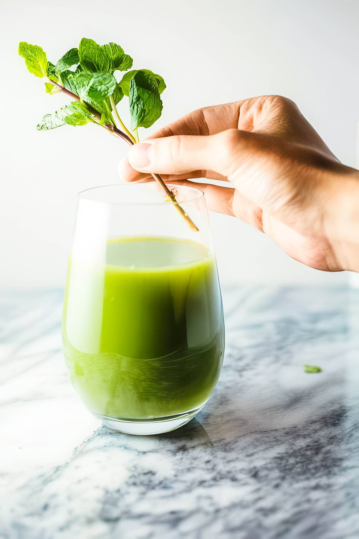Refreshing Cucumber Fruit Juice Recipe a glass of fresh cucumber fruit juce in a clear glass, with a fresh mint sprig being added