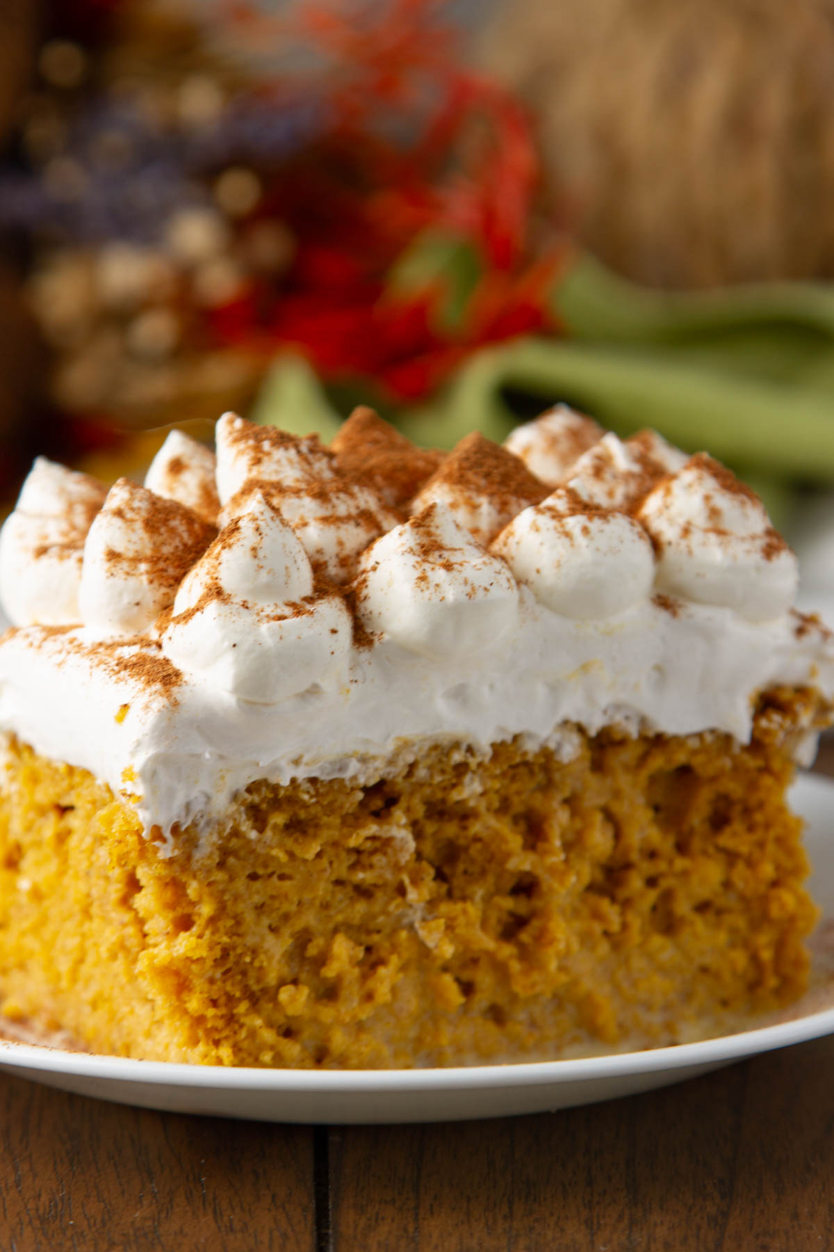 a slice of pumpkin tres leches cake on a small white plate on a wood table
