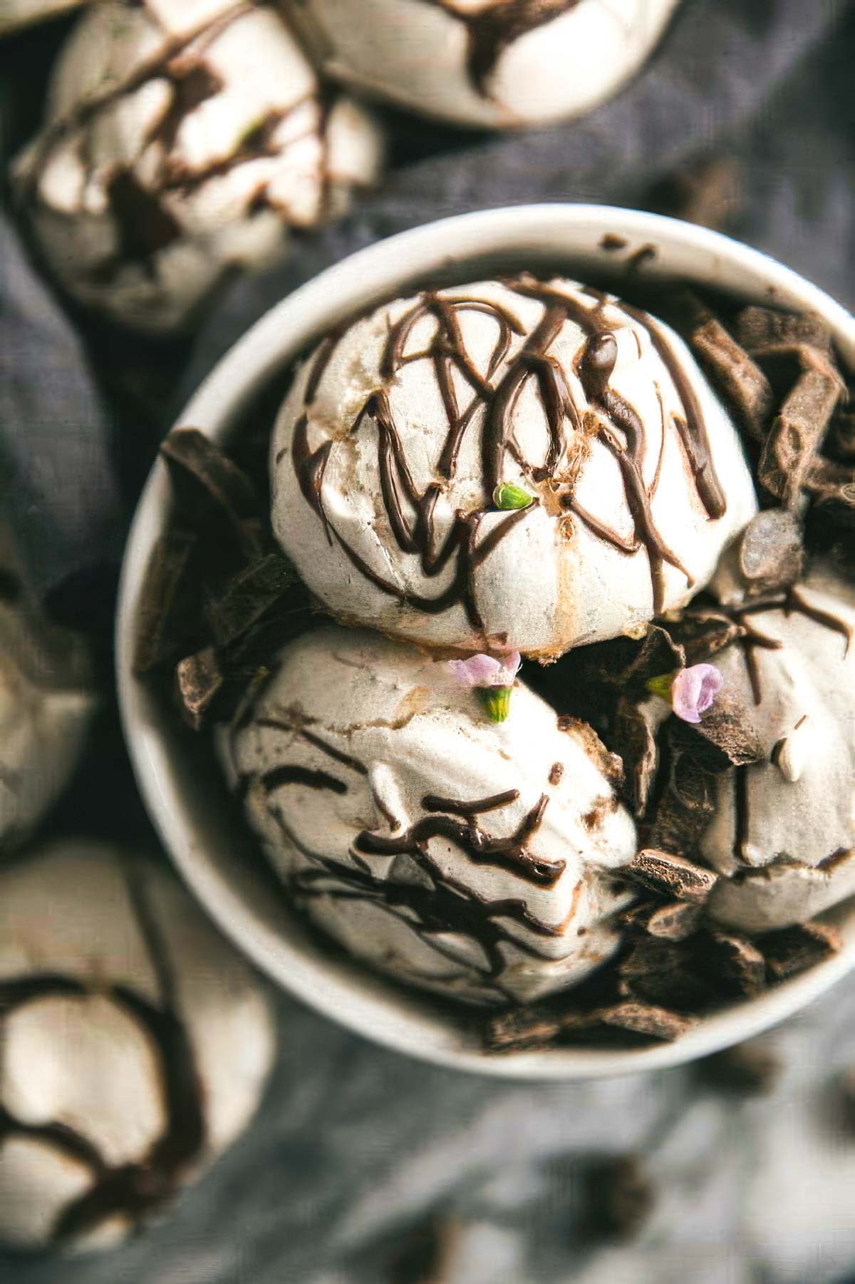 a white bowl filled with swirled chocolate meringue cookies with more cookies on the table around the bowl