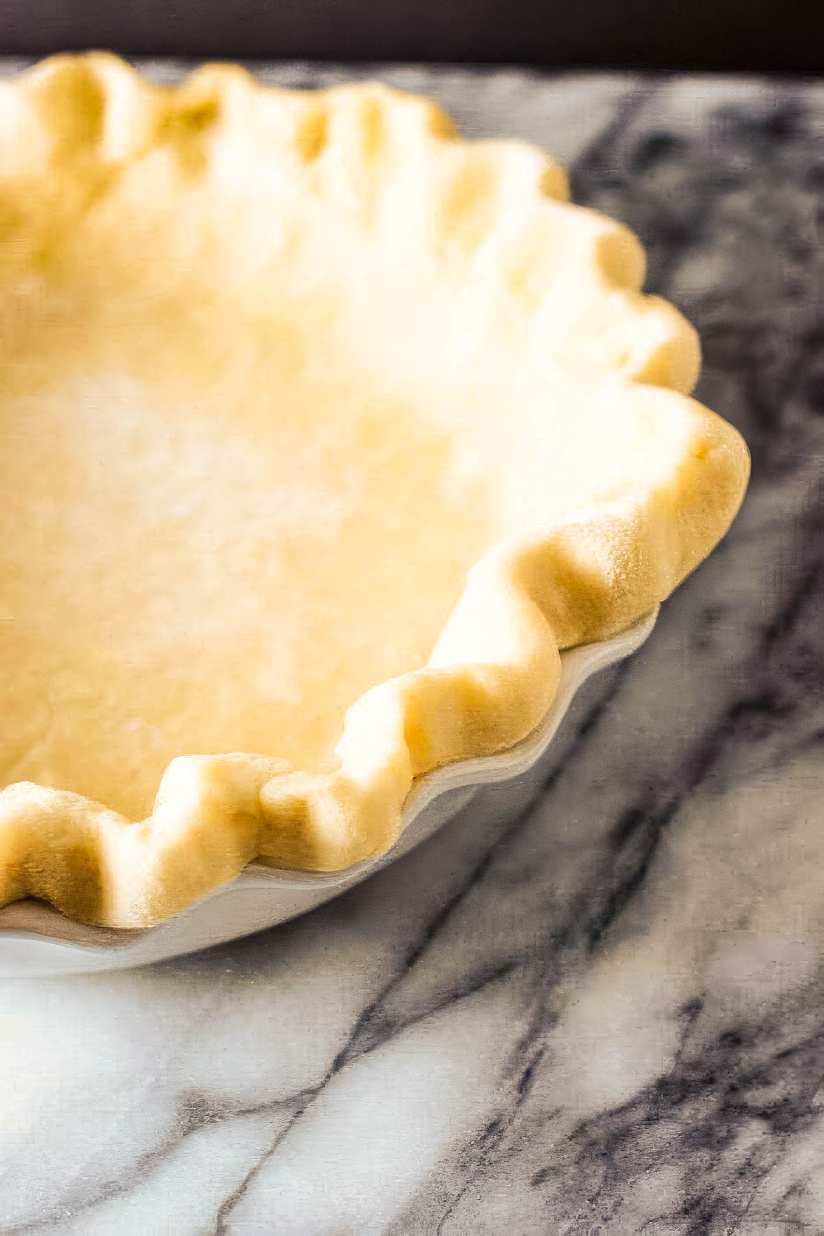 Step ten of making a homemade pie crust: a pie crust just out of the oven cools on a marble countertop
