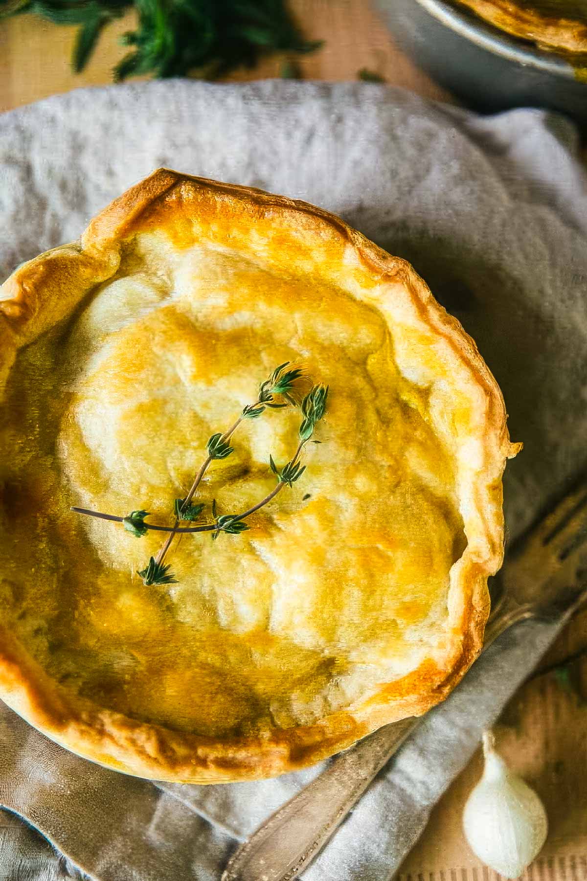 a homemade veggie pot pie just out of the oven with a golden brown crust and garnished with fresh thyme sprigs