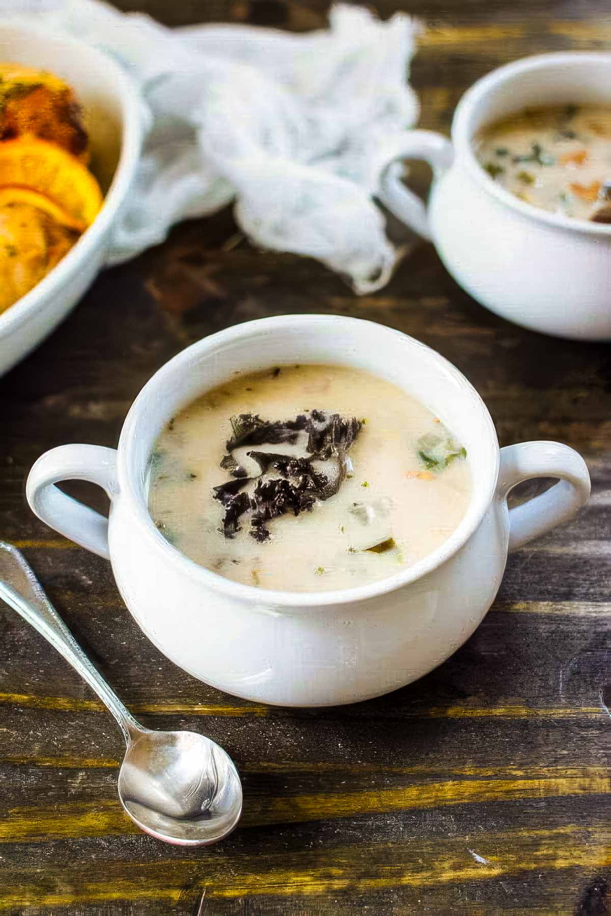 Cannellini Bean & Kale Soup two white bowls of cannellini bean and kale soup on a rustic wood table next to roasted chicken for dinner