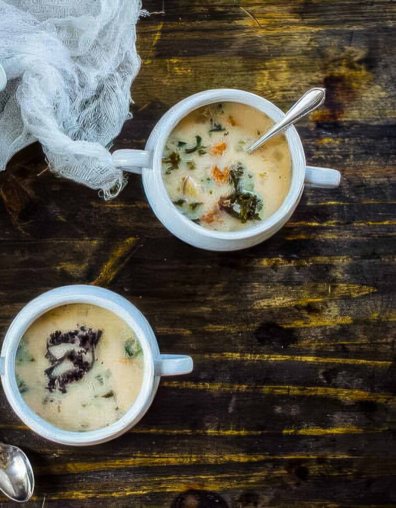 Cannellini Bean & Kale Soup an overhead shot of two white bowls of cannellini bean and kale soup on a rustic wood table