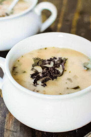 Cannellini Bean & Kale Soup two white bowls of cannellini bean and kale soup on a rustic wood table