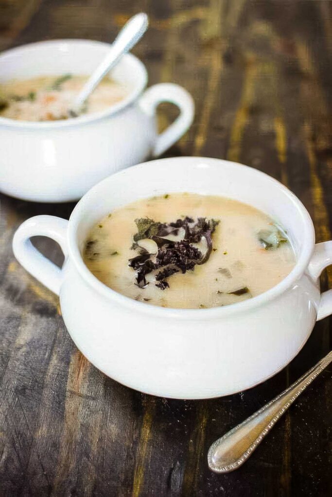 Cannellini Bean & Kale Soup two white bowls of cannellini bean and kale soup on a rustic wood table