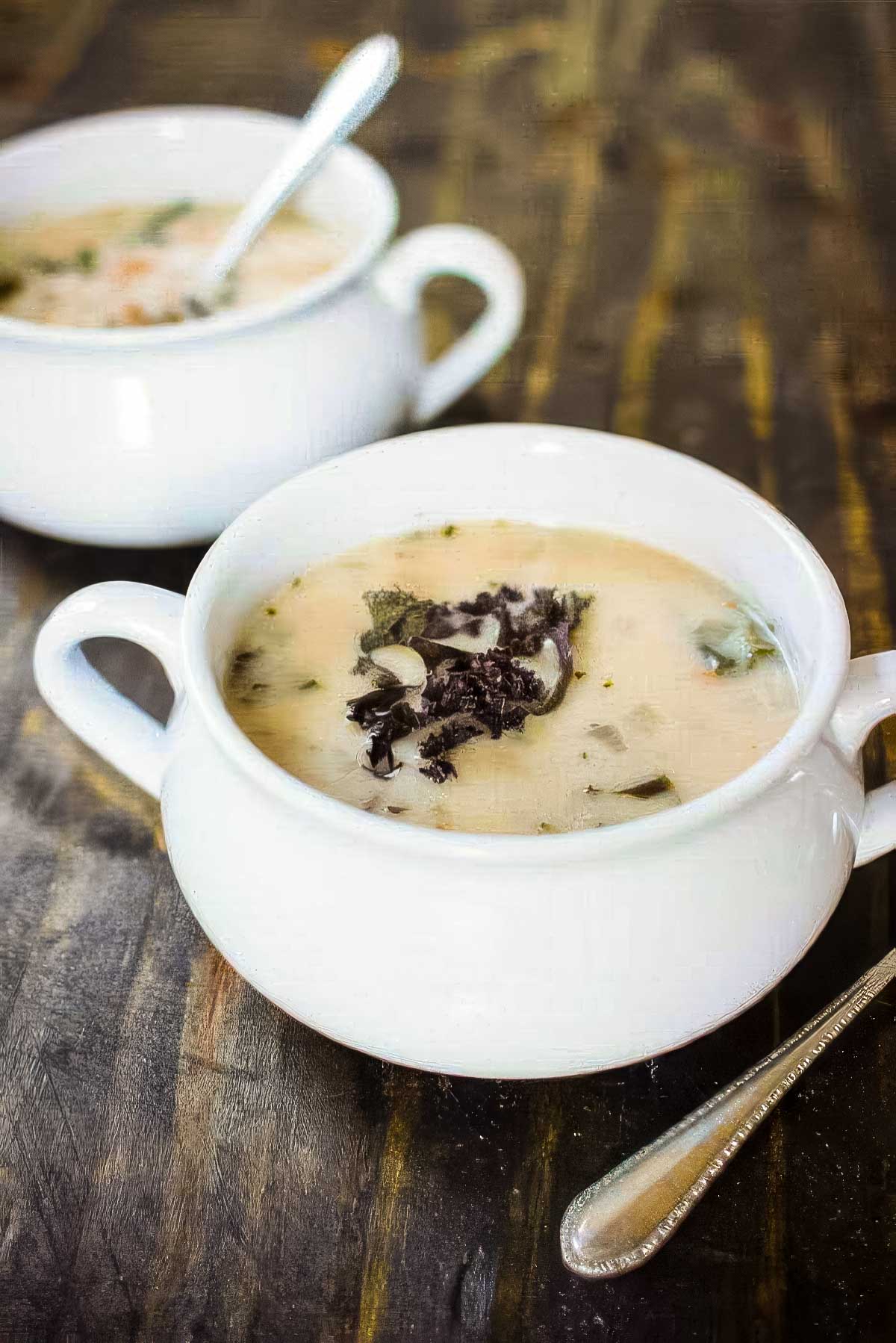 Cannellini Bean & Kale Soup two white bowls of cannellini bean and kale soup on a rustic wood table