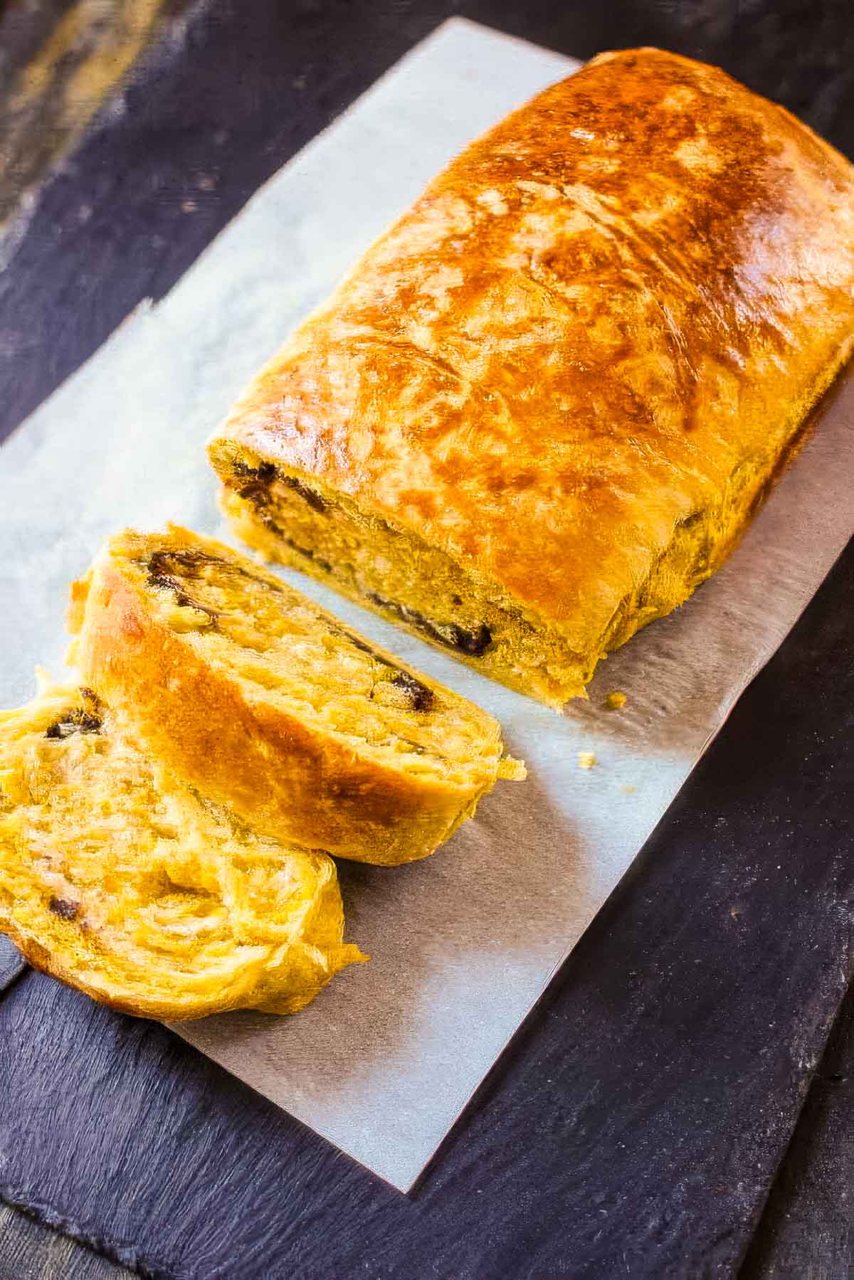 Pumpkin Brioche with Chocolate Swirl a top down view of a loaf of pumpkin brioche on a white cloth napkin with two slices cut out
