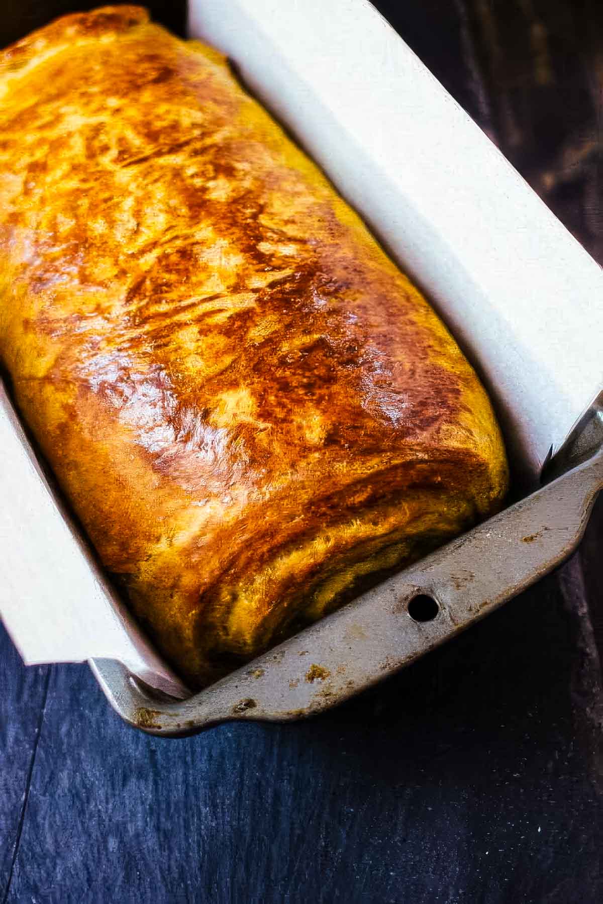 Pumpkin Brioche with Chocolate Swirl a loaf of pumpkin brioche bread in a loaf pan just out of the oven