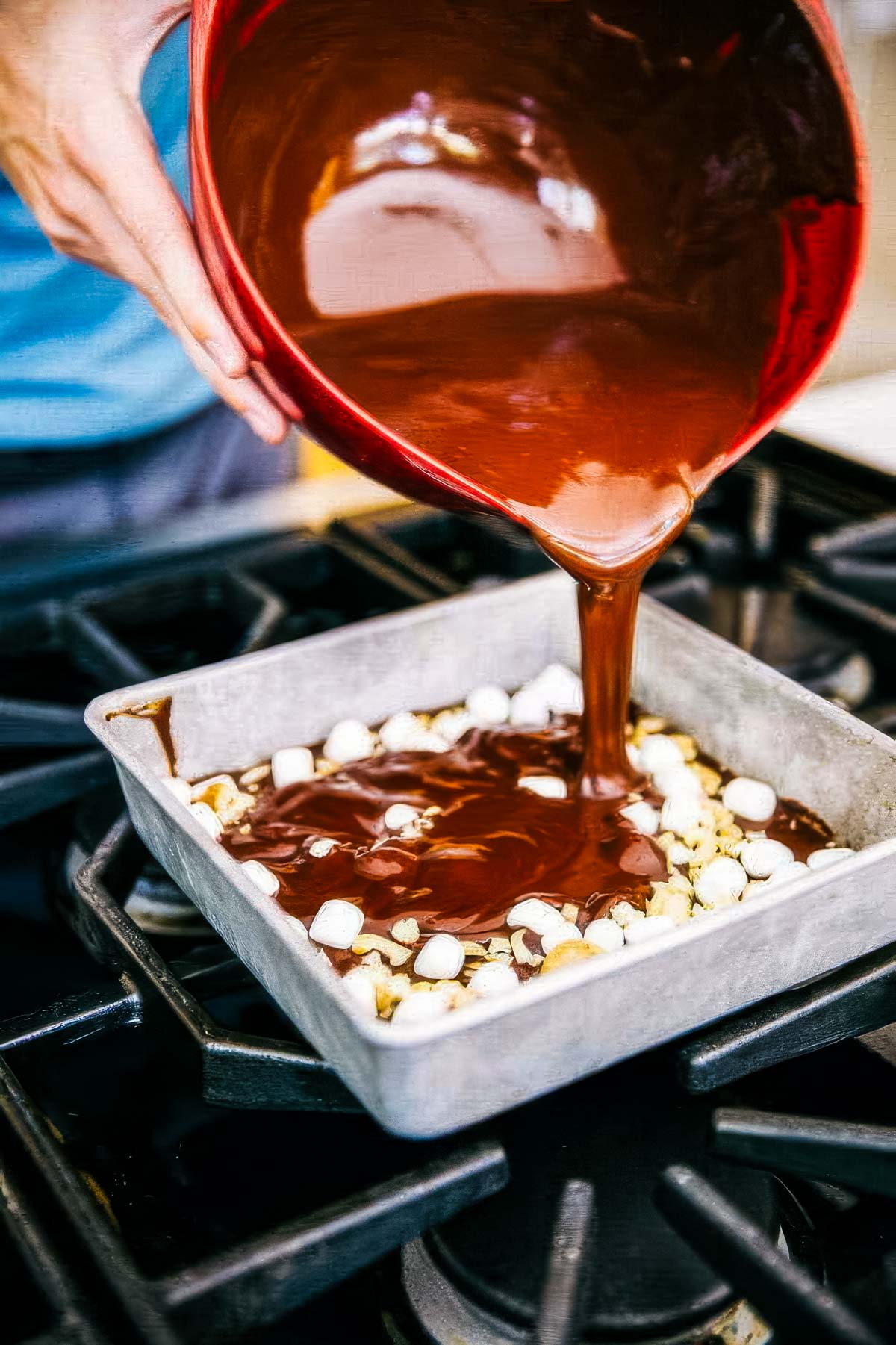 No-Bake Rocky Road Bars with Cashews step 5 for making rocky road bars: melted chocolate being poured over the first two layers