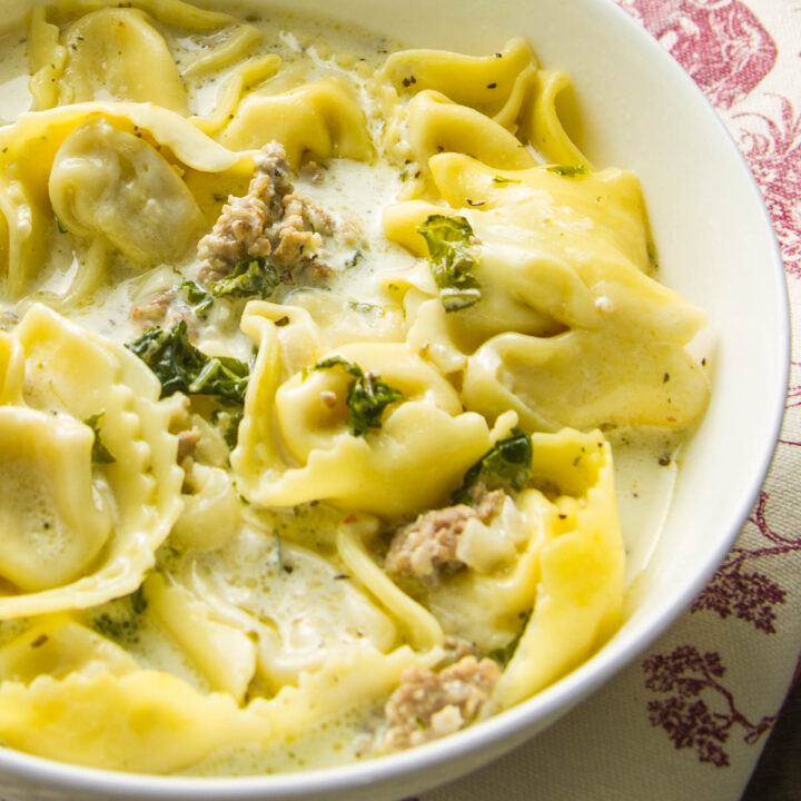 a hearty bowl of sausage tortellini soup with kale and cream