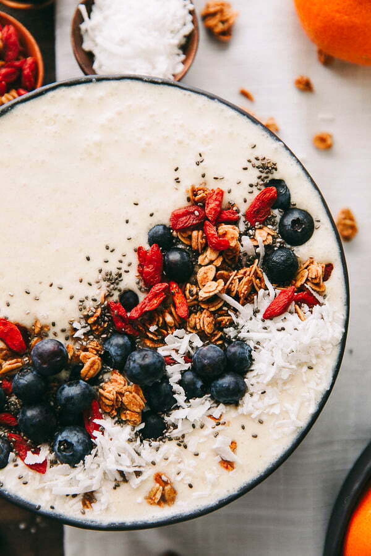 Coconut Smoothie Bowl a closeup of a coconut smoothie bowl topped with fresh blueberries, granola, and goji berries