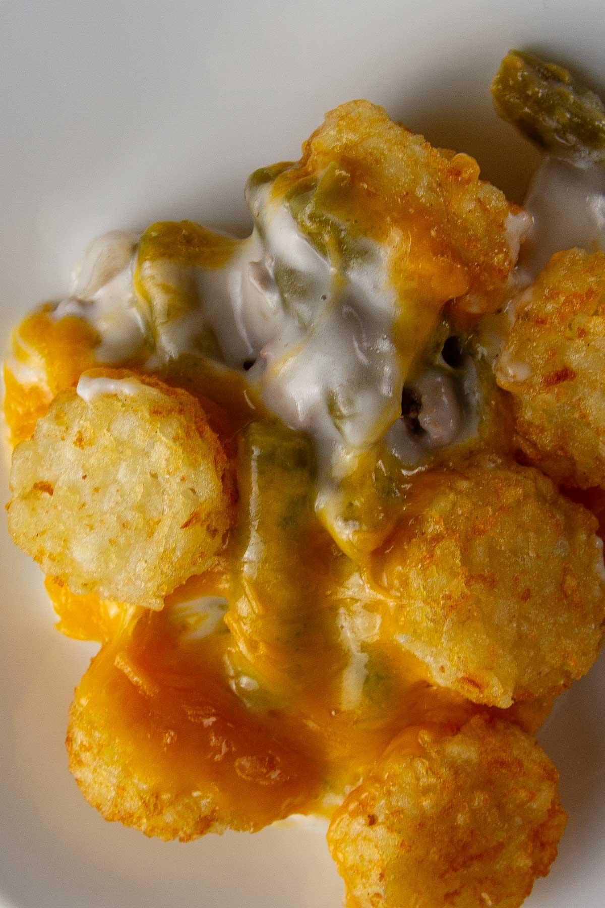 a closeup of a white plate with a serving of easy tater tot casserole