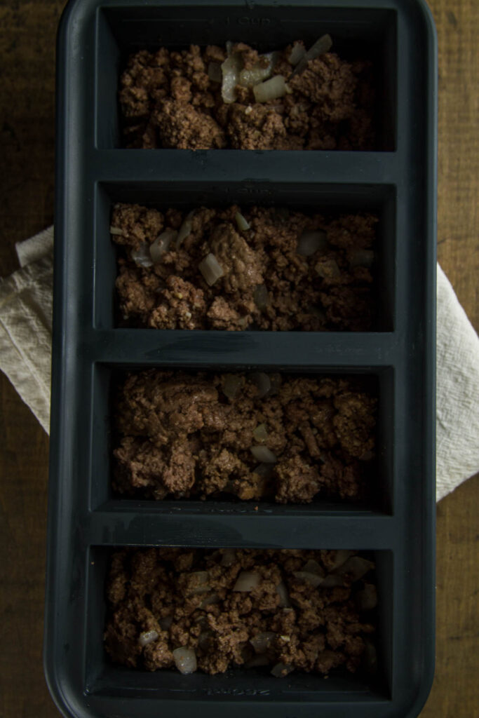 Easy Tater Tot Casserole a 1-cup souper cube tray filled with cooked ground beef, onions, and garlic, the first layer in easy tater tot casserole