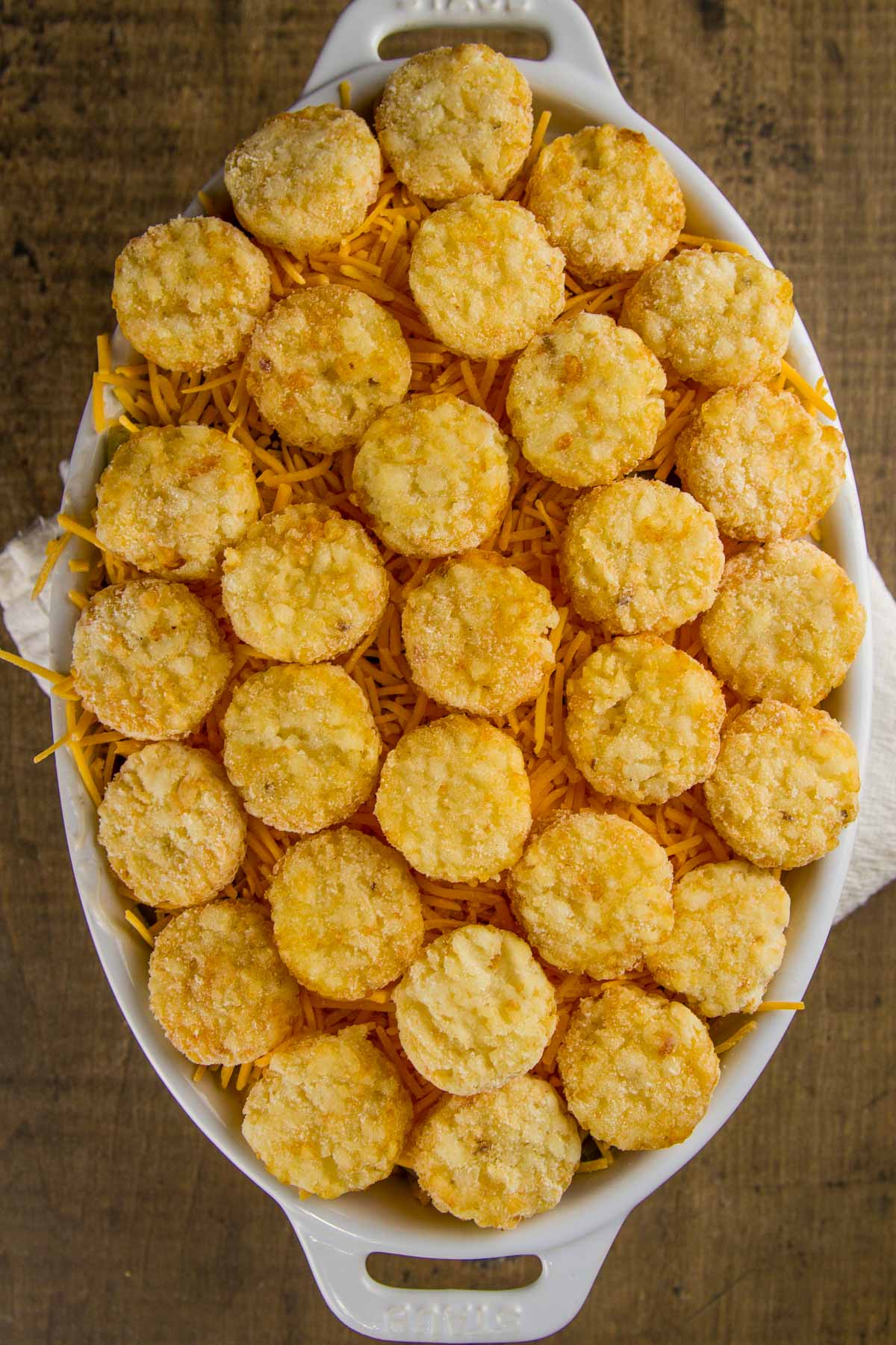 Easy Tater Tot Casserole an easy tater tot casserole fully assembled in an oval casserole dish ready for the oven