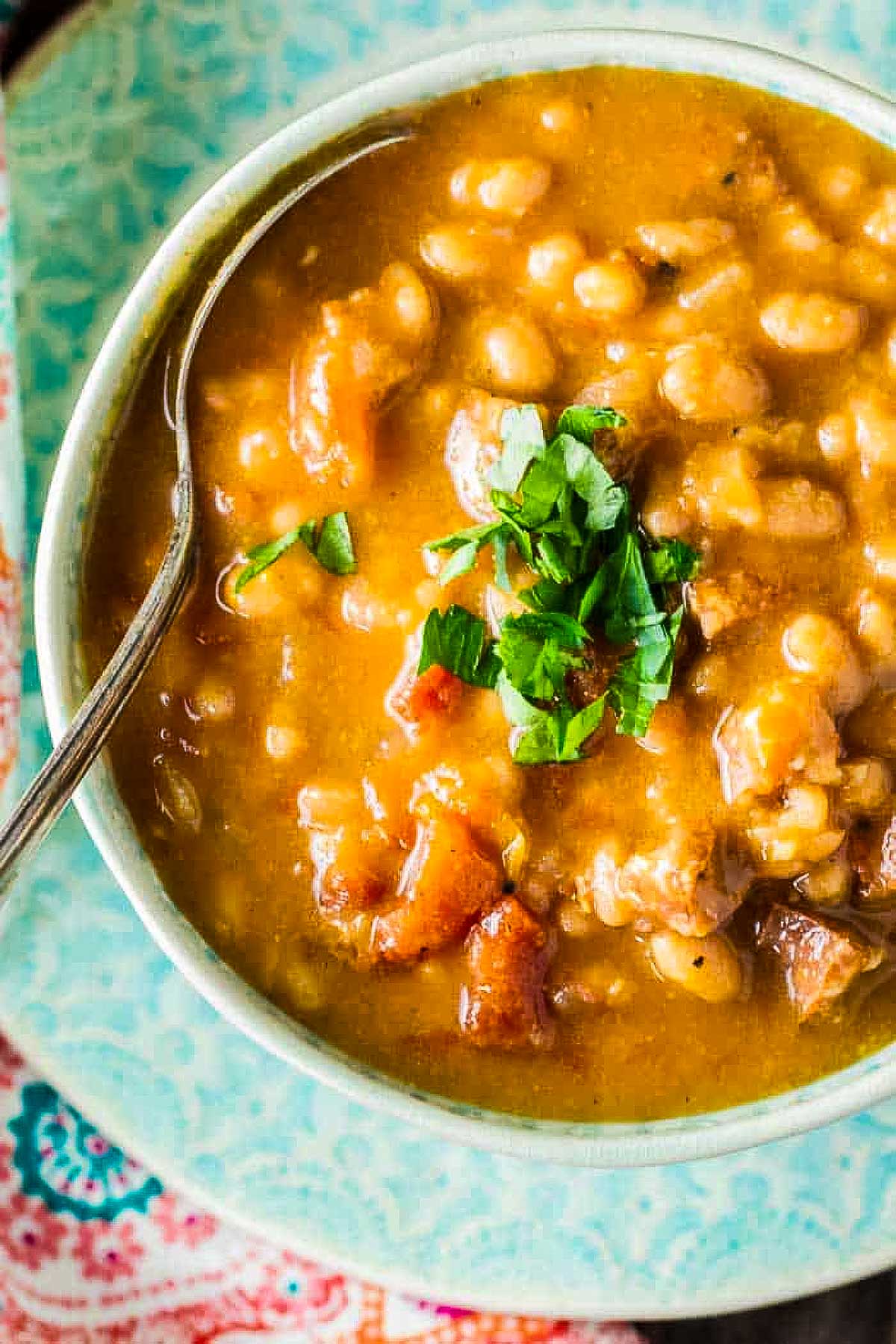 Sausage Bean Soup (Stovetop or Instant Pot) an overhead shot of sausage bean soup with a spoon and garnished with chopped fresh parsley