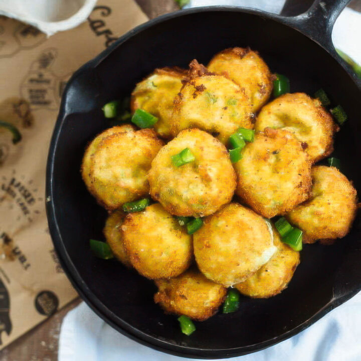 a pan of spicy cheese fritters on a white towel on a wood table