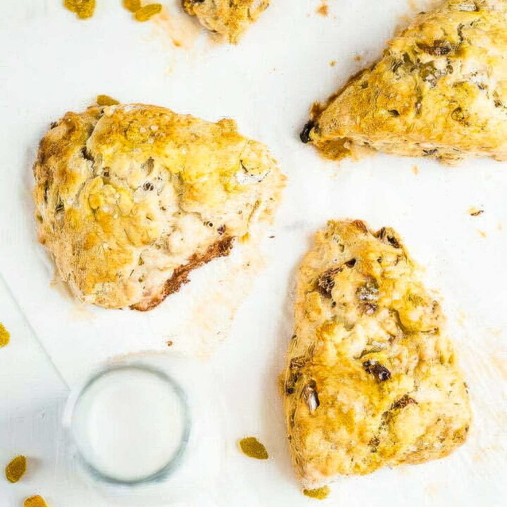 three irish soda bread scones on parchment paper next to a glass of milk