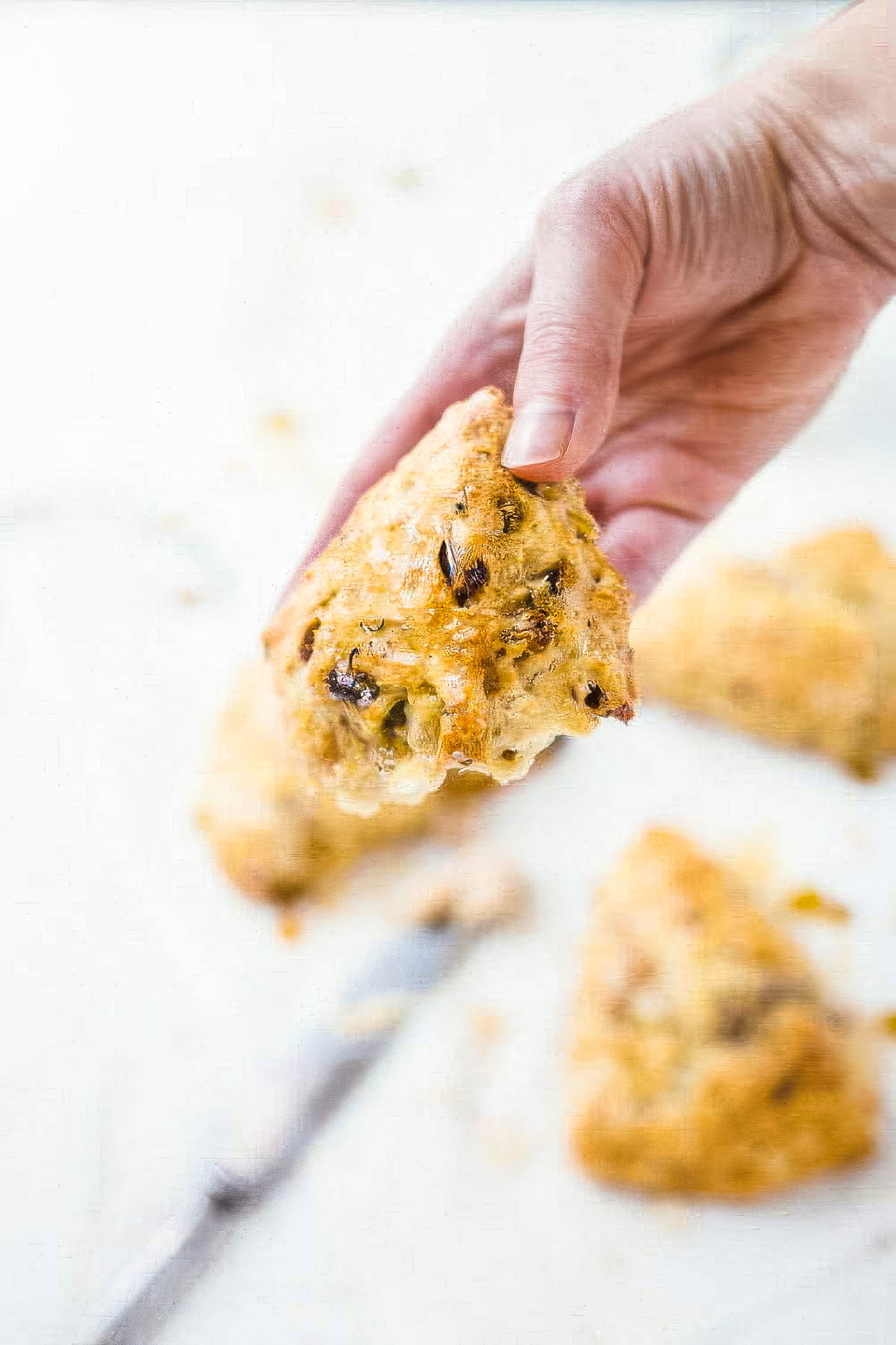 Irish Soda Bread Scones with Cinnamon Honey Butter a hand holding an irish soda bread scone