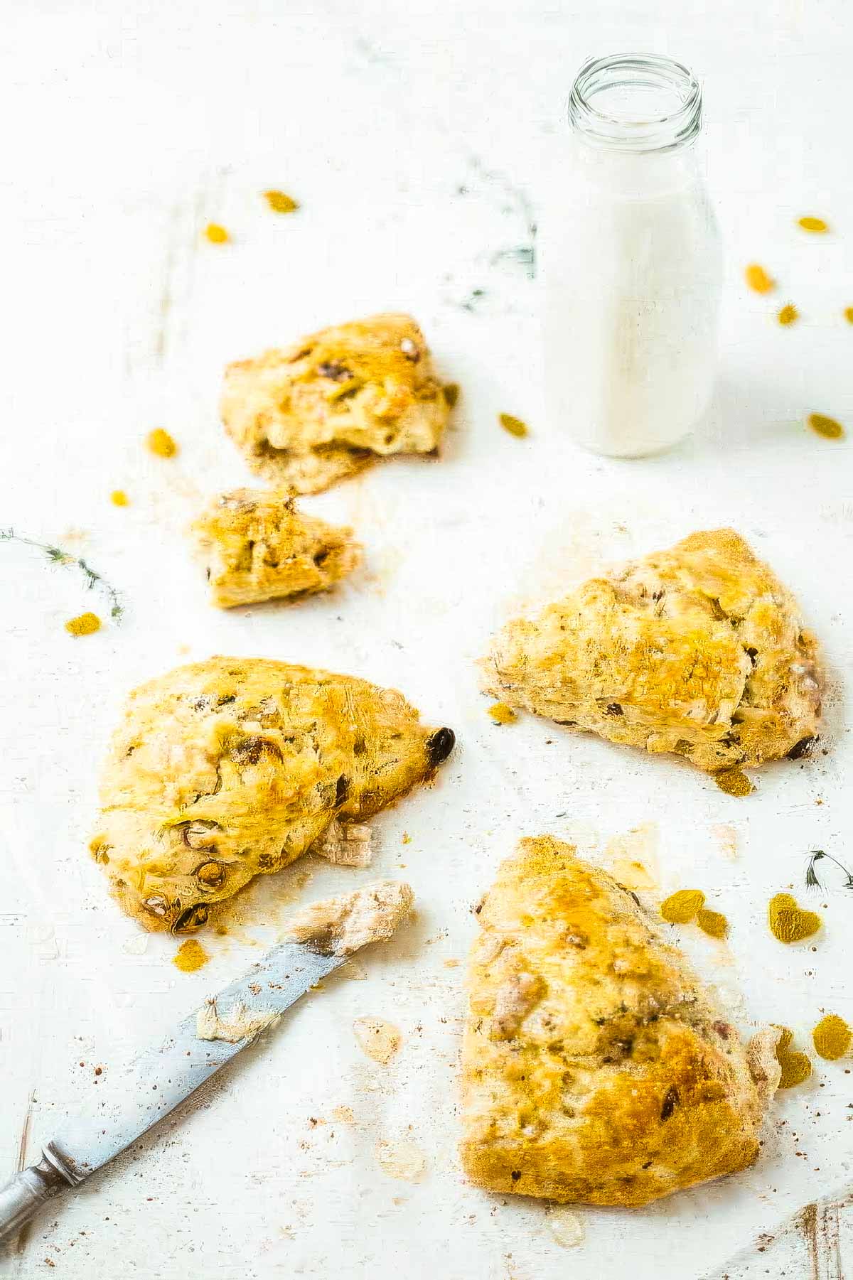 Irish Soda Bread Scones with Cinnamon Honey Butter several irish soda bread scones on parchment paper next to a knife and a glass of milk