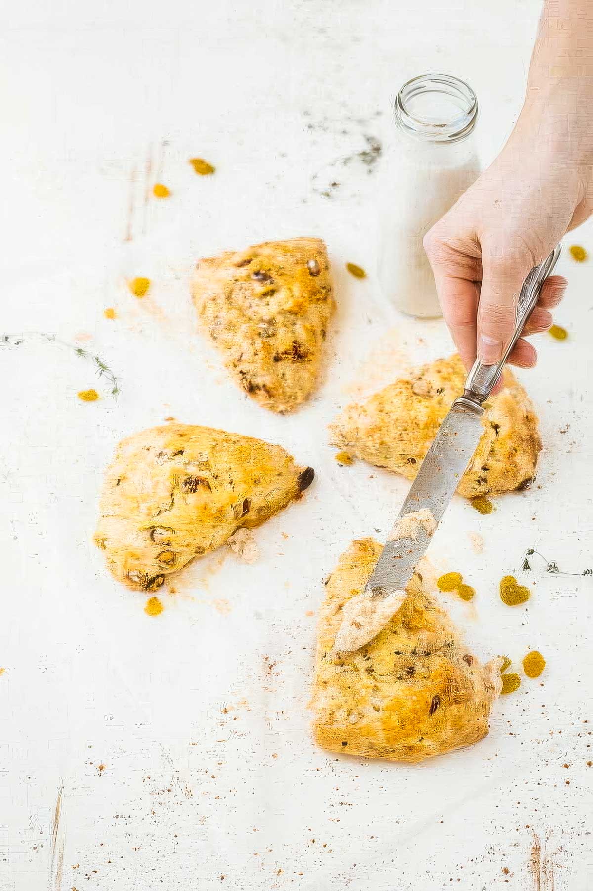 Irish Soda Bread Scones with Cinnamon Honey Butter freshly baked irish soda bread scones with a hand holding a knife, about to spread cinnamon butter on the hot scones