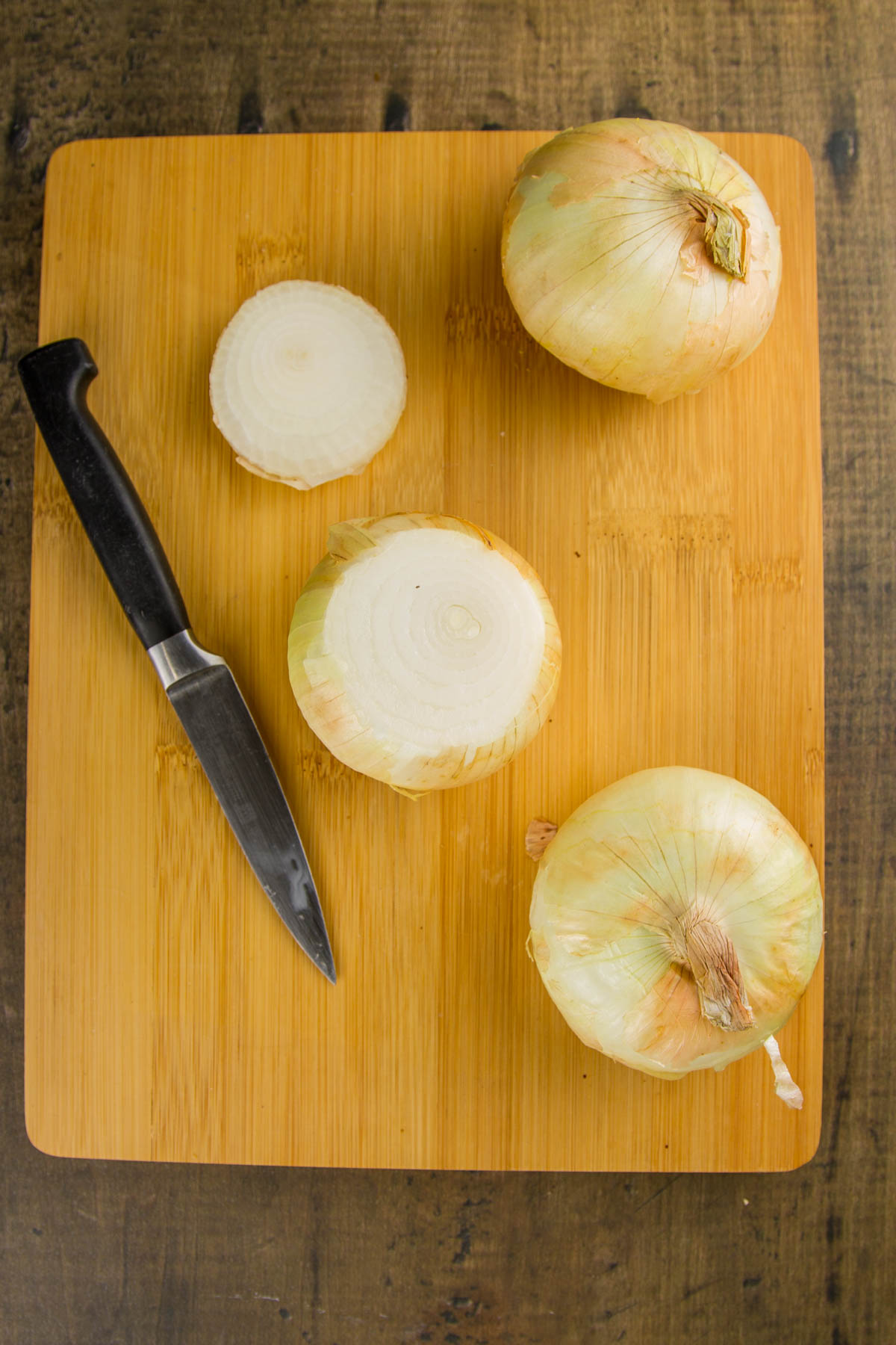 Whole Oven Roasted Onions (+ 33 Ways to Use Them!) an image showing step 2 for how to make whole oven roasted onions (an onion with the root end being cut off)