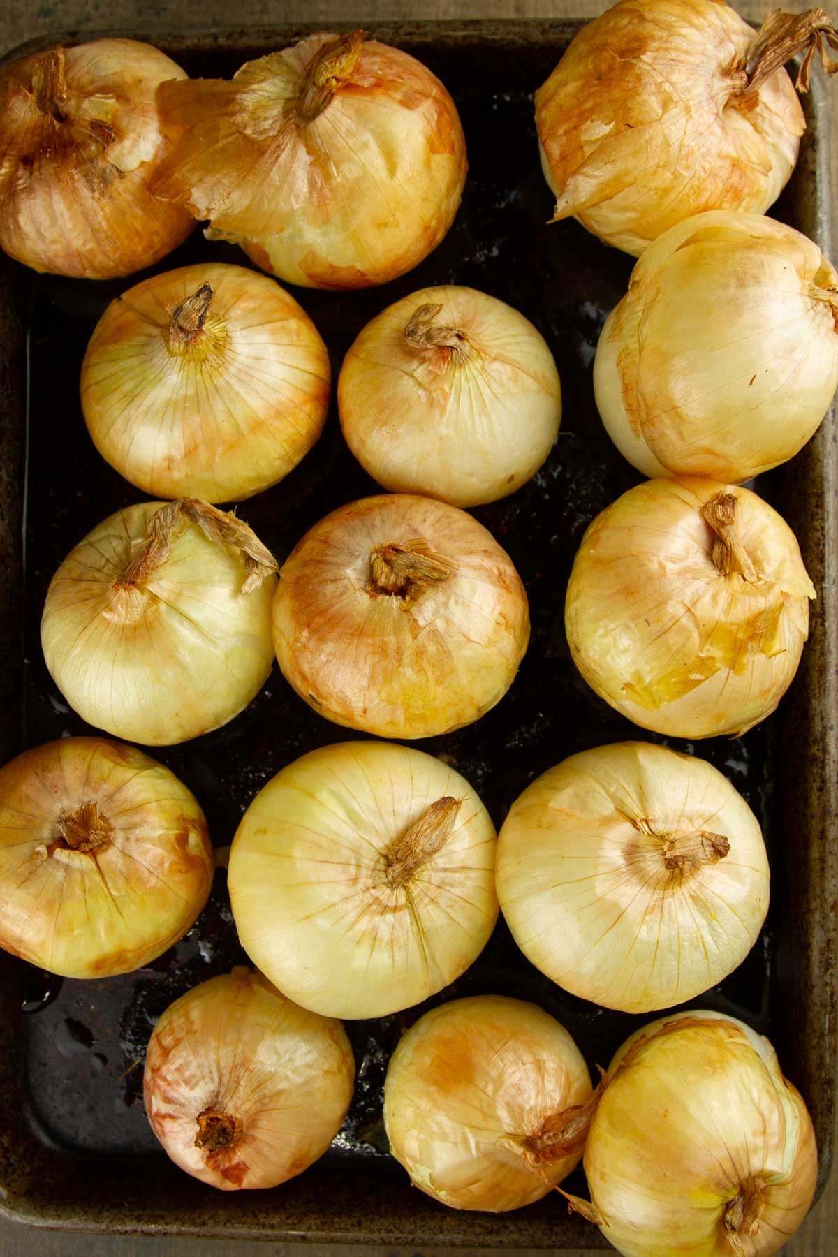 Whole Oven Roasted Onions (+ 33 Ways to Use Them!) step 4 when making whole oven roasted onions: a sheet pan filled with whole onions after having been roasted in the oven for 45 minutes