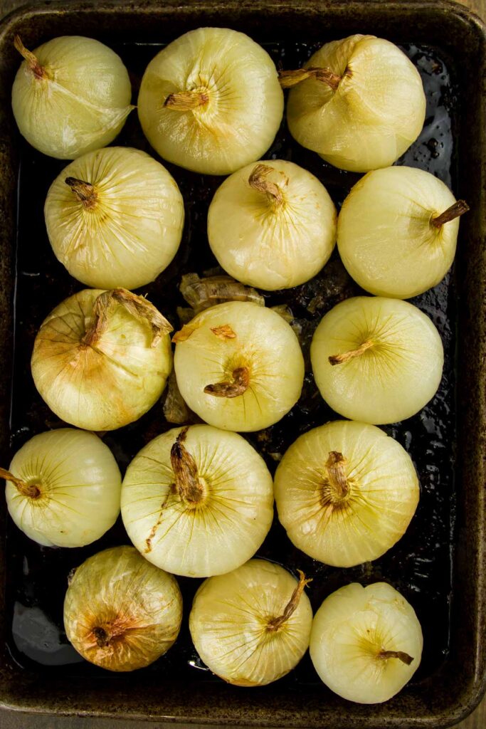 Whole Oven Roasted Onions (+ 33 Ways to Use Them!) step 5 when making whole oven roasted onions: a sheet pan filled with whole oven roasted onions after they've cooled and the skins have been removed