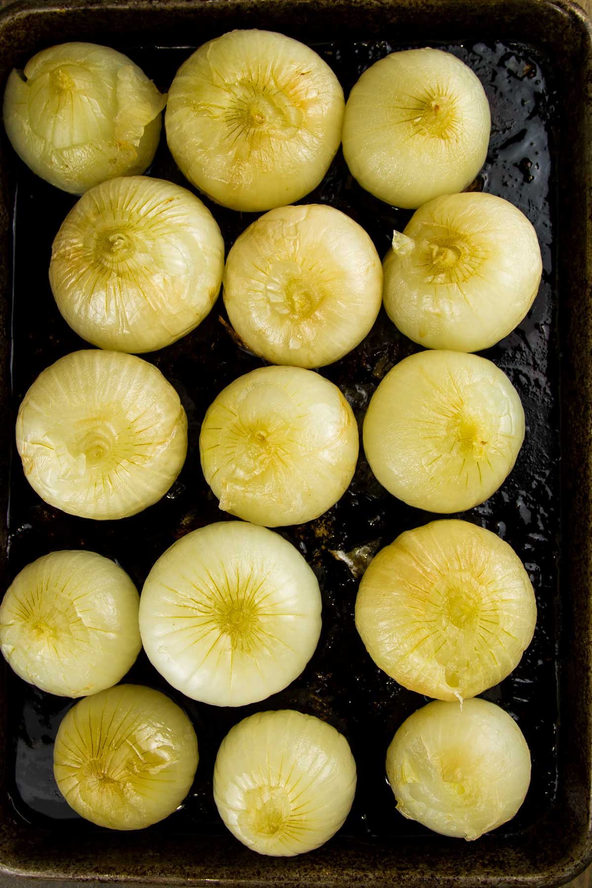 Whole Oven Roasted Onions (+ 33 Ways to Use Them!) step 6 when making whole oven roasted onions: a sheet pan filled with whole oven roasted onions after they've cooled and the skins have been removed, the tops cut off, and they're ready to be enjoyed