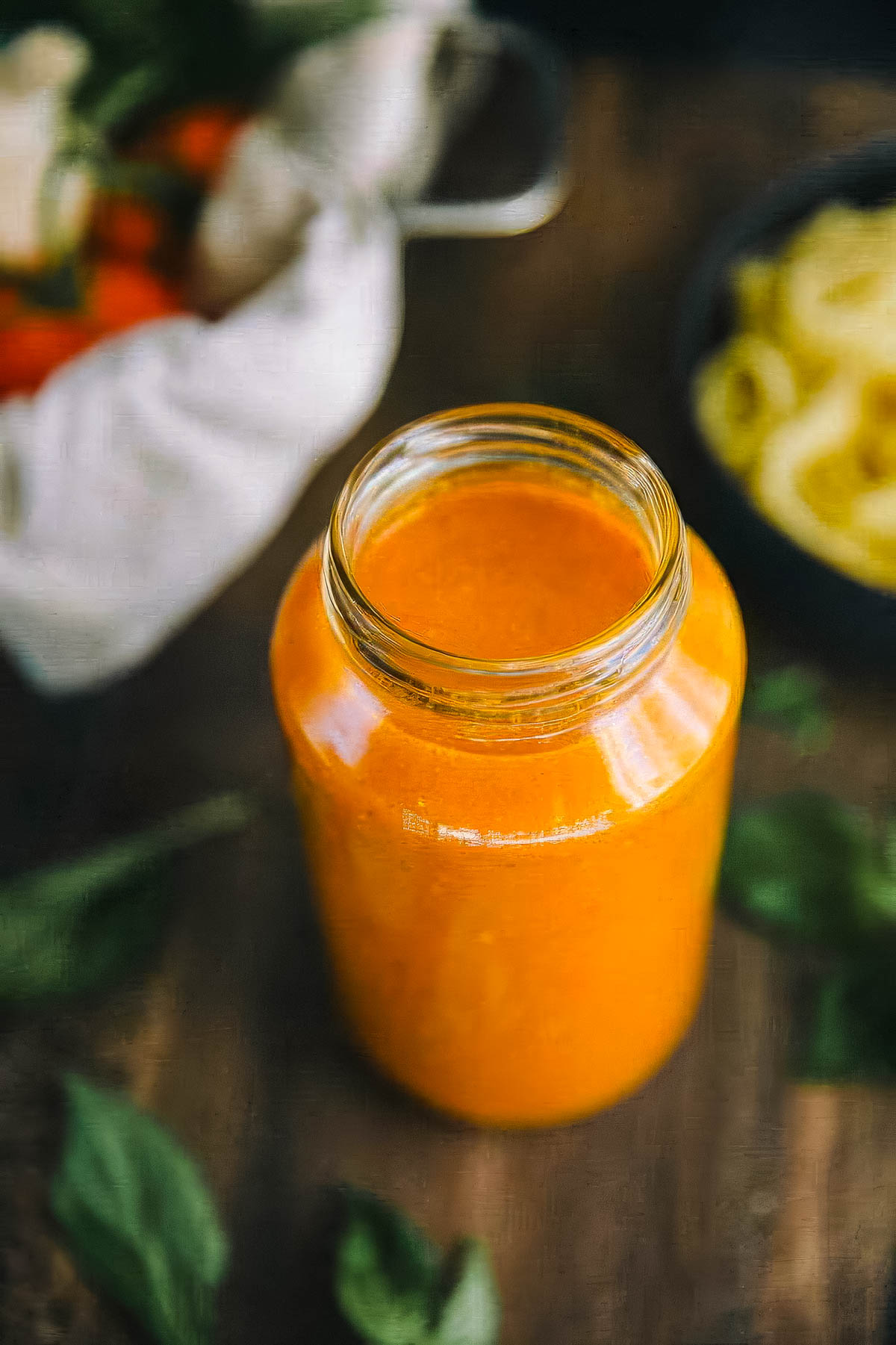 a jar of authentic italian marinara sauce next to a bowl of cooked pasta and a bowl of tomatoes on the vine