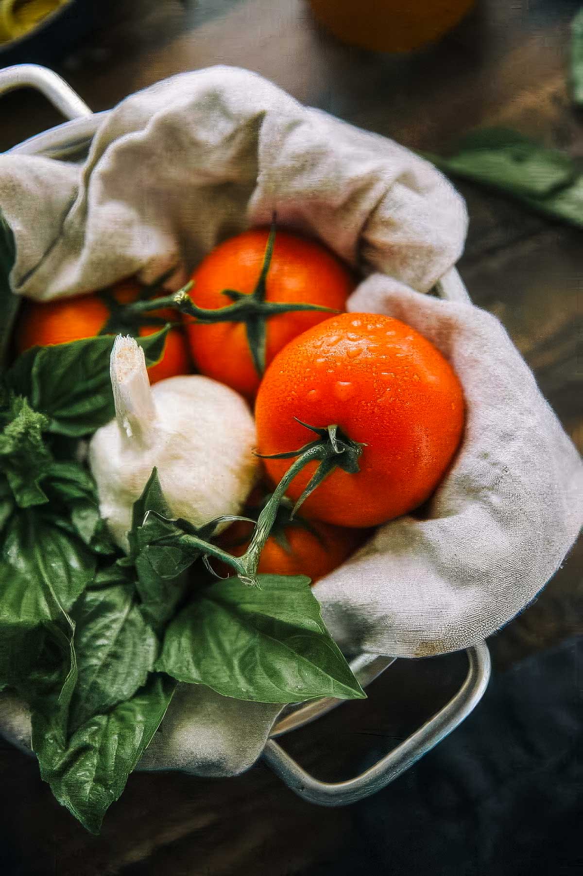 Authentic Italian Marinara Sauce a basket filled with fresh ingredients for authentic italian marinara sauce (tomatoes, basil, and garlic)