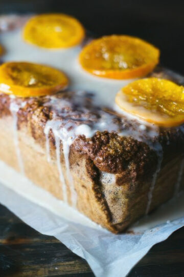 a clementine quick bread recipe showing the completed loaf dripping with icing and topped with candied clementines