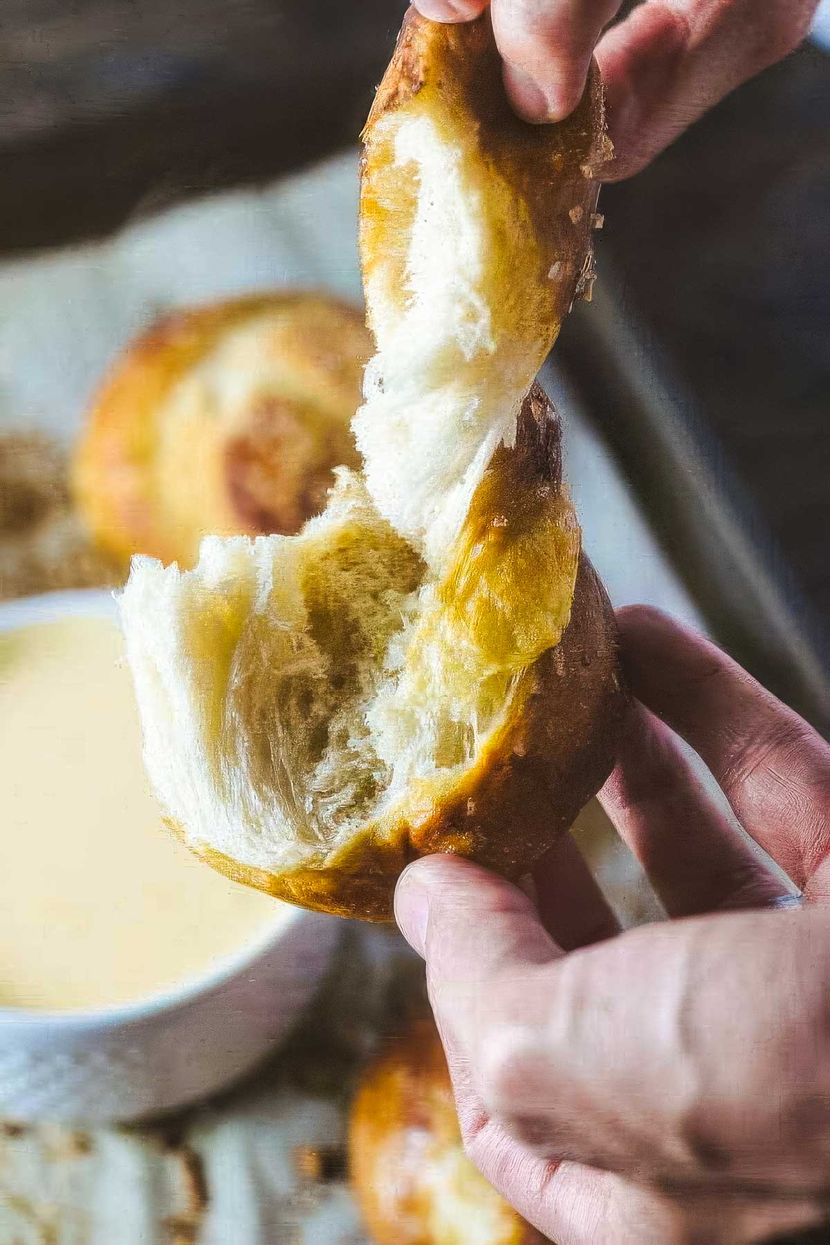 Garlic Pretzel Knots with Cheese Dipping Sauce a person pulling apart a warm garlic pretzel knot