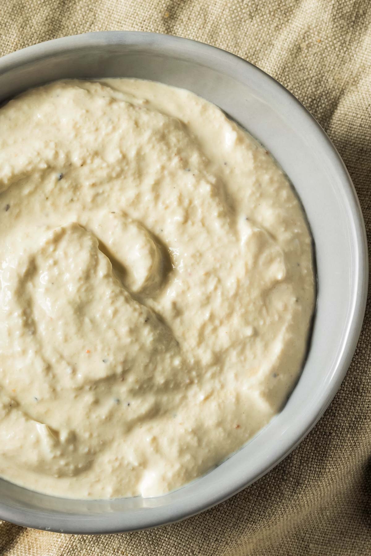 a closeup of a gray bowl filled with horseradish sauce just before serving with prime rib