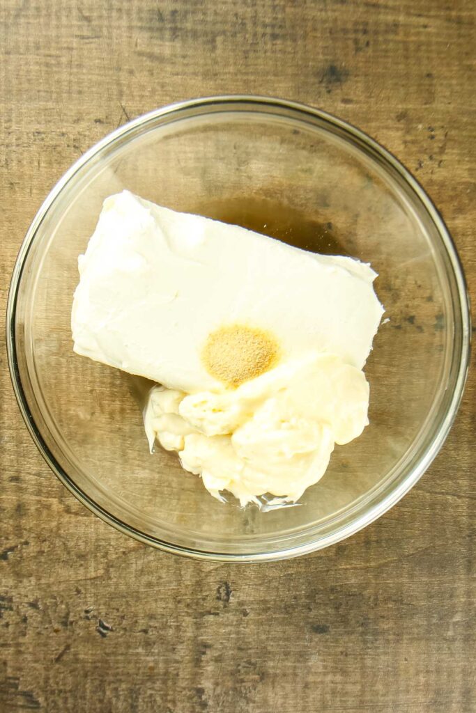 Ingredients for cream cheese olive dip in a clear mixing bowl just before being mixed together